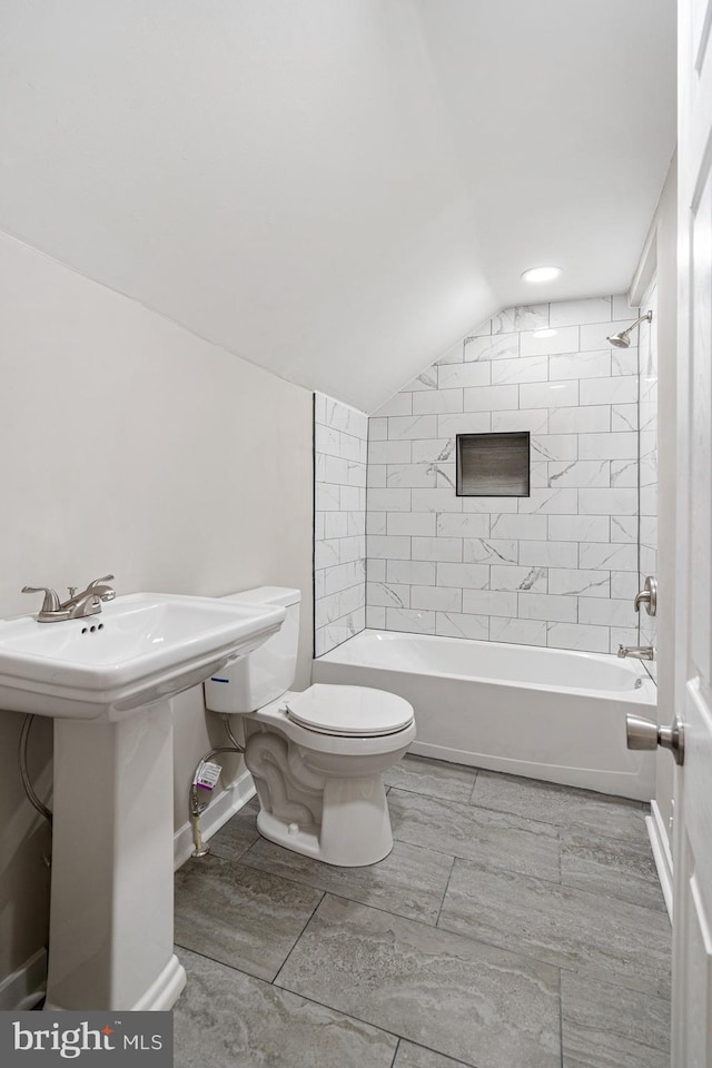 full bathroom with sink, vaulted ceiling, tiled shower / bath, and toilet