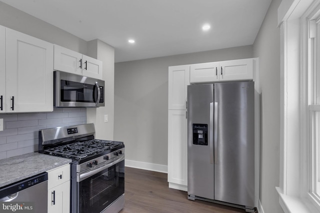 kitchen with dark wood-type flooring, appliances with stainless steel finishes, tasteful backsplash, light stone countertops, and white cabinets