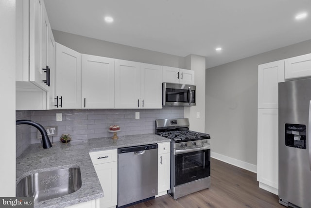 kitchen with white cabinetry, appliances with stainless steel finishes, sink, and light stone counters