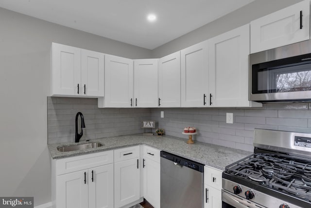 kitchen featuring white cabinetry, sink, light stone counters, and stainless steel appliances