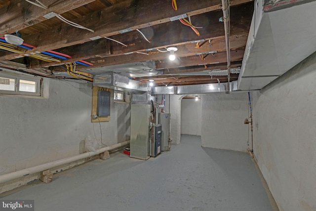 basement featuring electric panel, heating unit, and gas water heater