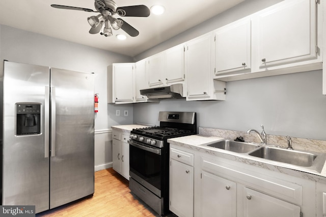 kitchen featuring light countertops, appliances with stainless steel finishes, white cabinetry, a sink, and under cabinet range hood