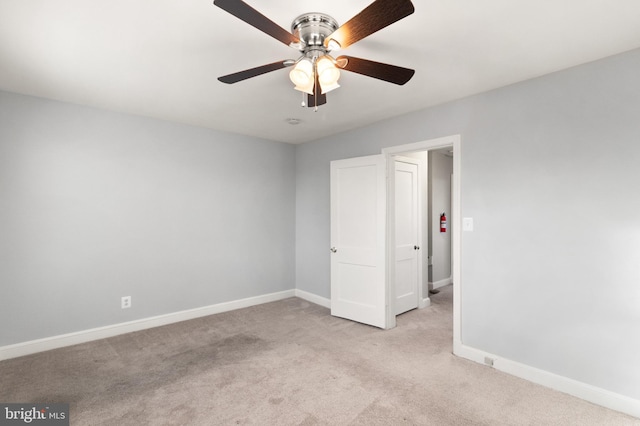 unfurnished bedroom with light carpet, a ceiling fan, and baseboards