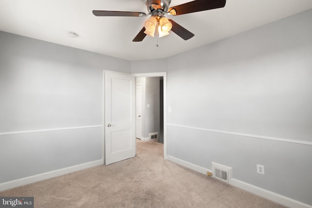 unfurnished room with baseboards, a ceiling fan, visible vents, and light colored carpet