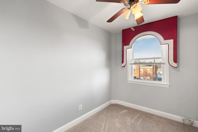 carpeted spare room with ceiling fan and baseboards