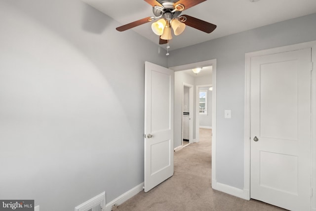 unfurnished bedroom featuring visible vents, baseboards, a ceiling fan, and light colored carpet