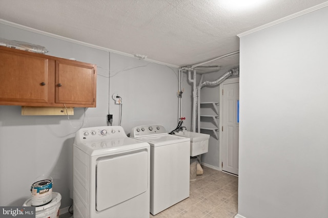 washroom featuring cabinet space, a sink, washer and clothes dryer, and a textured ceiling