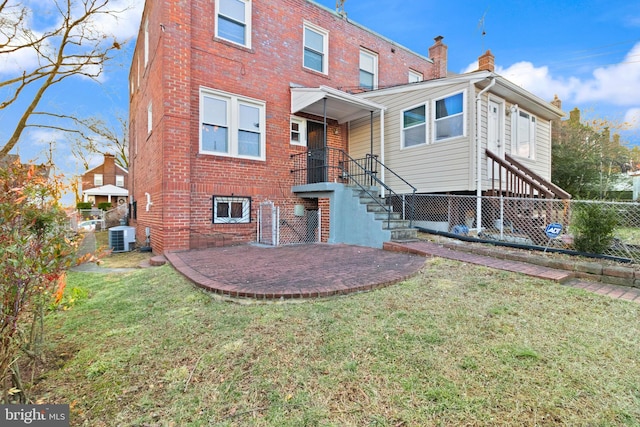 rear view of house featuring a chimney, fence, a yard, central air condition unit, and brick siding