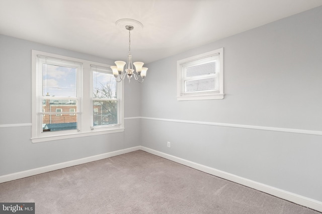 spare room featuring carpet, baseboards, and an inviting chandelier