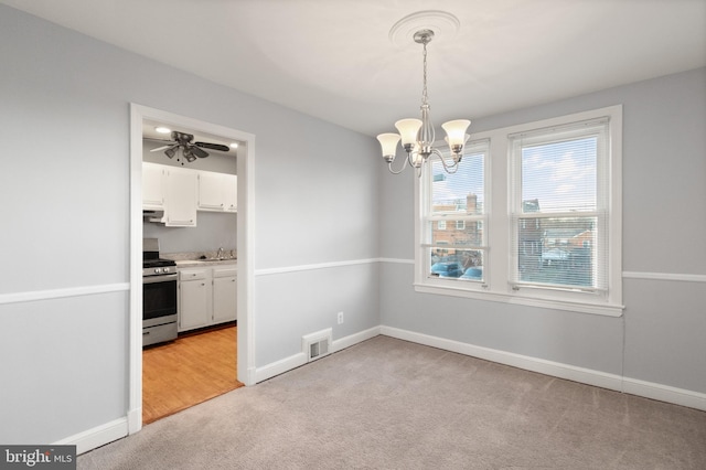 unfurnished dining area featuring light carpet, a sink, visible vents, and baseboards