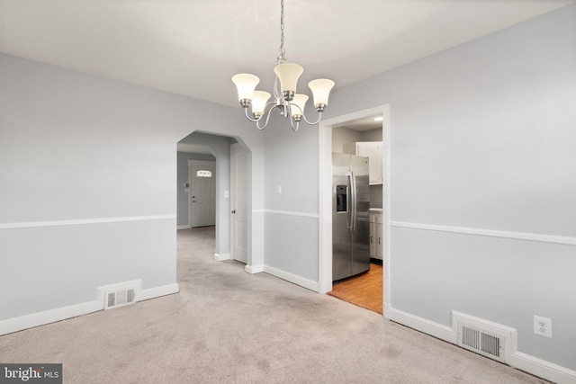 unfurnished dining area with carpet, visible vents, arched walkways, and baseboards