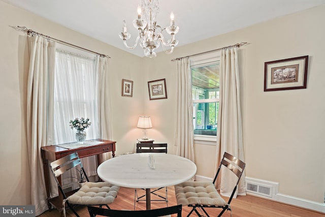 dining area featuring hardwood / wood-style flooring and an inviting chandelier