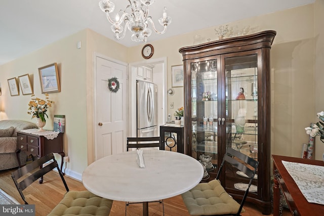 dining area with an inviting chandelier and light hardwood / wood-style flooring