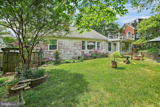 rear view of house featuring a balcony and a yard