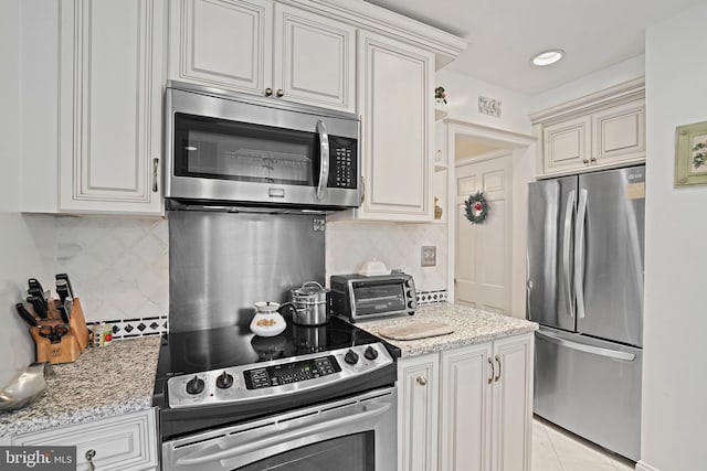 kitchen with stainless steel appliances, light tile patterned flooring, light stone countertops, and backsplash