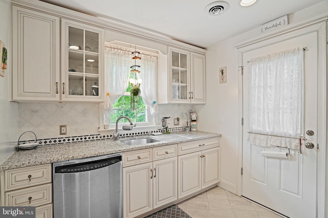 kitchen featuring light tile patterned flooring, sink, stainless steel dishwasher, cream cabinets, and decorative backsplash