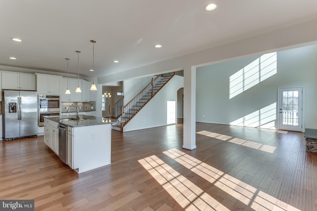 kitchen with white cabinetry, sink, stainless steel appliances, and a center island with sink