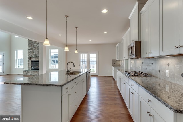 kitchen with pendant lighting, sink, appliances with stainless steel finishes, a spacious island, and stone countertops