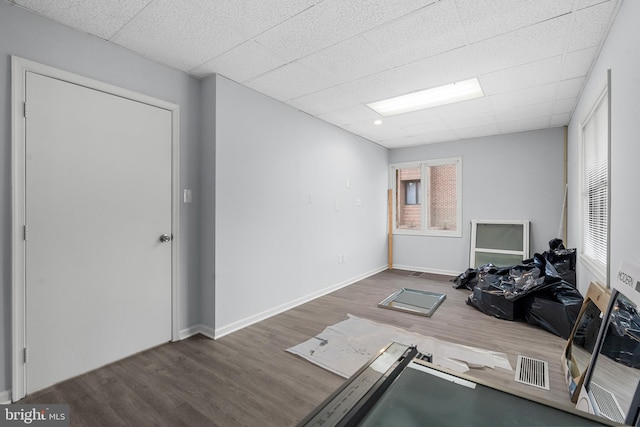 exercise room with dark hardwood / wood-style flooring and a drop ceiling