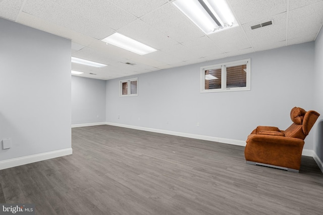 basement with dark wood-type flooring and a paneled ceiling