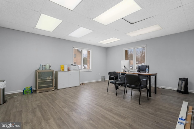 office space with a paneled ceiling, a healthy amount of sunlight, and dark wood-type flooring