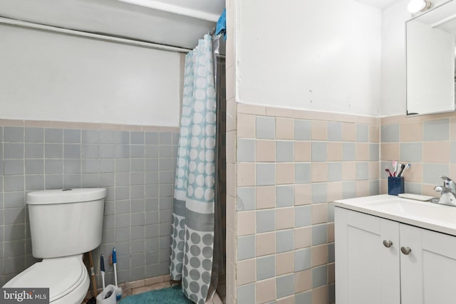 bathroom with toilet, tile walls, vanity, and a shower with curtain