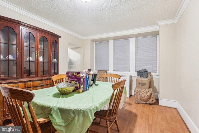 dining room with light hardwood / wood-style floors, a textured ceiling, and ornamental molding