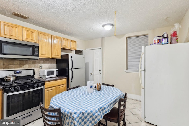 kitchen featuring appliances with stainless steel finishes, tasteful backsplash, light brown cabinets, and light tile patterned floors