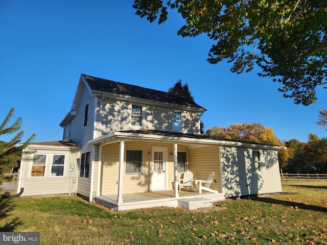 rear view of house with covered porch and a lawn