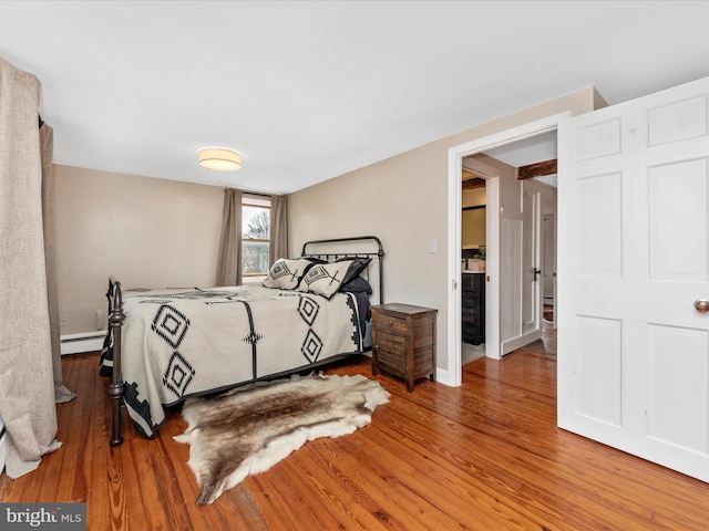 bedroom with a baseboard radiator and hardwood / wood-style floors