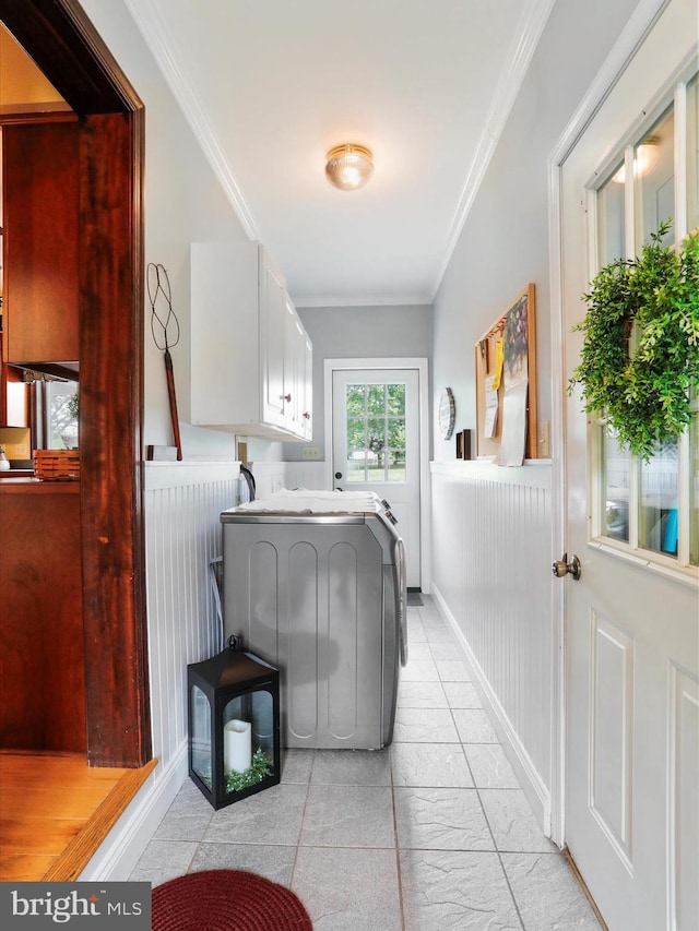 laundry room featuring washer and dryer, crown molding, and cabinets