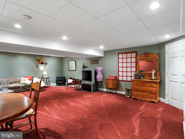 interior space with carpet floors, a paneled ceiling, and a wood stove