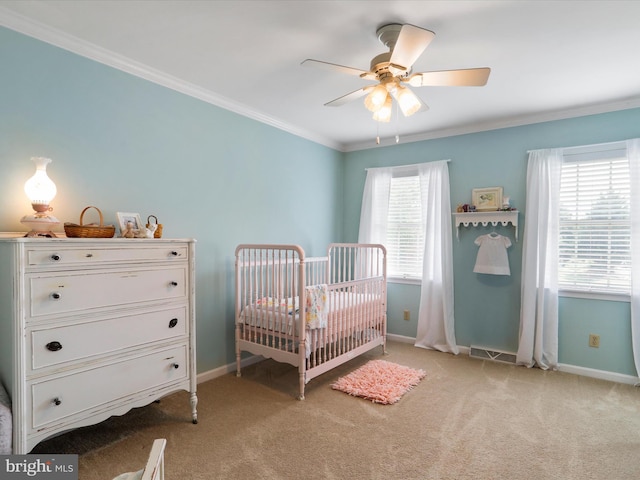 bedroom with a crib, ornamental molding, light colored carpet, and ceiling fan