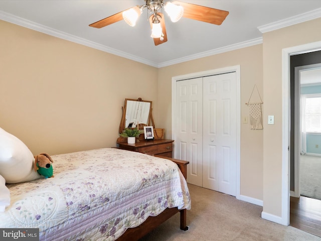 carpeted bedroom with ornamental molding, a closet, and ceiling fan