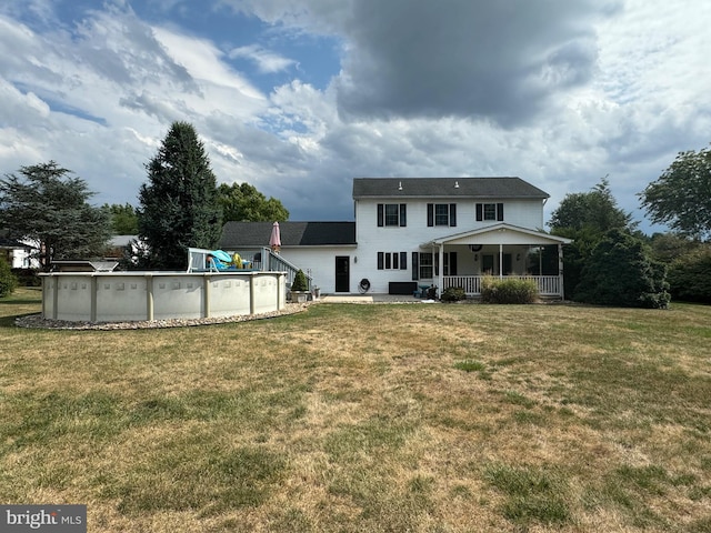 rear view of property featuring a yard and covered porch