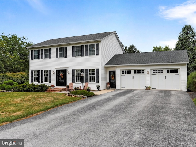 colonial-style house featuring a garage and a front yard