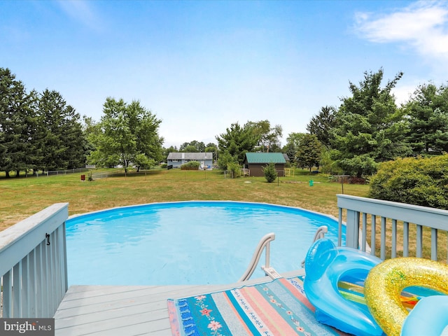 view of swimming pool featuring a wooden deck and a yard