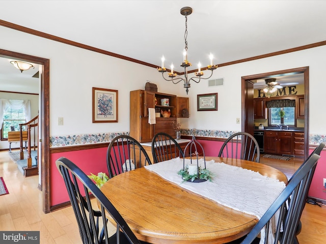 dining area featuring sink, crown molding, light hardwood / wood-style flooring, and ceiling fan with notable chandelier