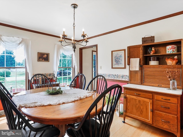 dining area featuring crown molding, a notable chandelier, and light hardwood / wood-style flooring