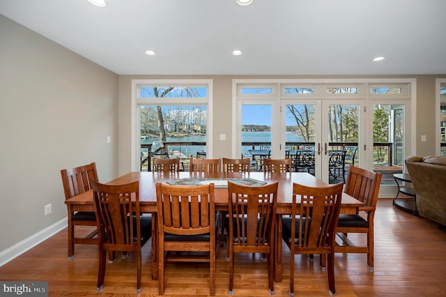 dining area featuring hardwood / wood-style flooring, a water view, a wealth of natural light, and french doors