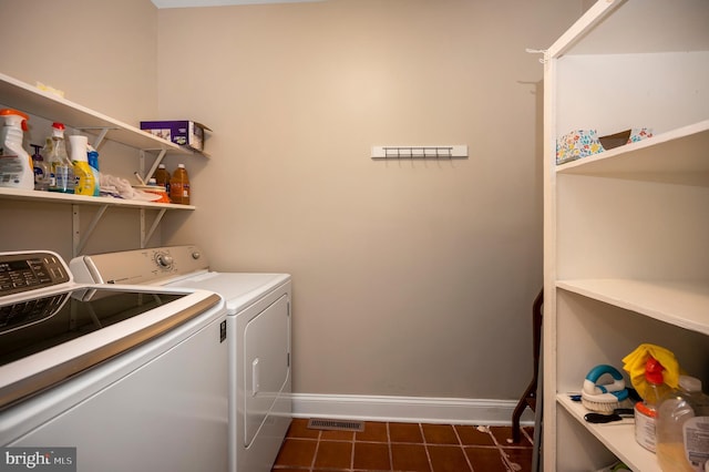 laundry room with independent washer and dryer and dark tile patterned flooring