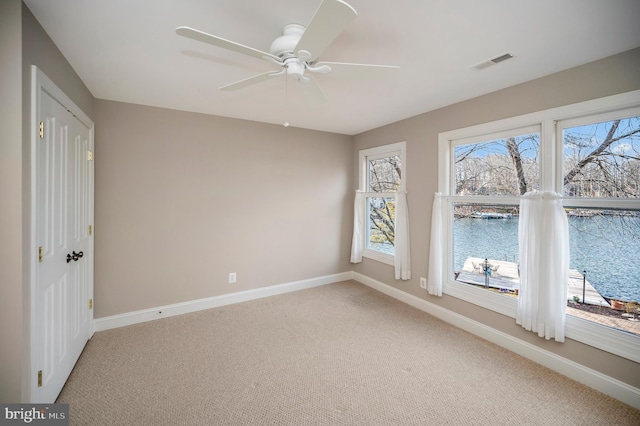 empty room with a water view, carpet flooring, and ceiling fan