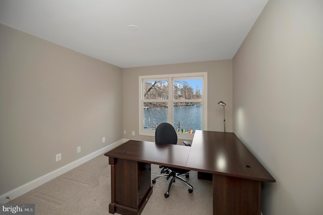 home office with light carpet and a water view