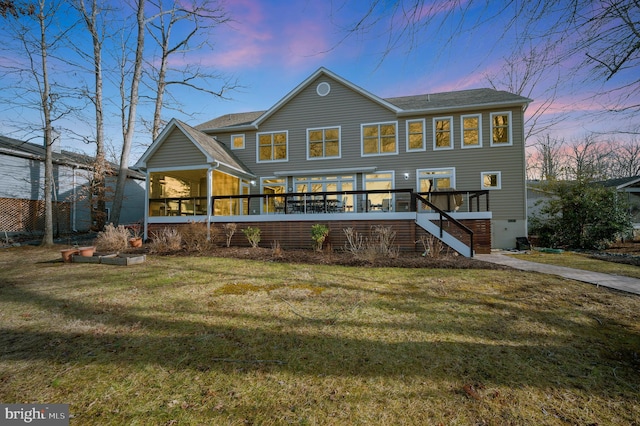 view of front of home with a wooden deck, a sunroom, and a lawn