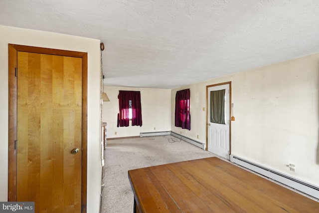 carpeted empty room featuring a baseboard heating unit and a textured ceiling