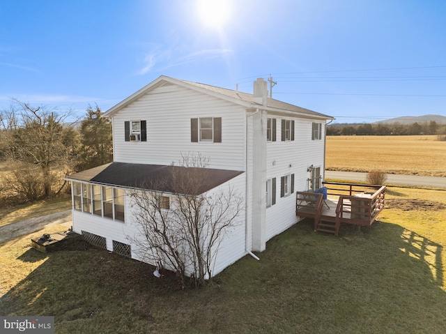 view of side of property with a sunroom, a yard, and a deck