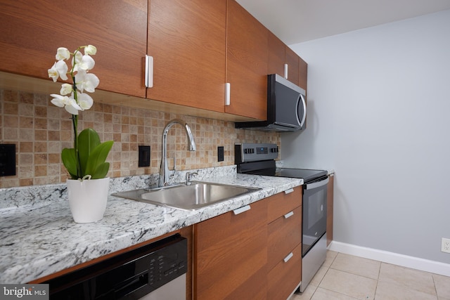 kitchen featuring light tile patterned flooring, sink, light stone counters, tasteful backsplash, and stainless steel appliances