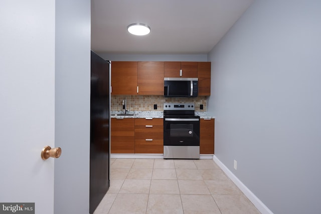 kitchen featuring stainless steel appliances, sink, light tile patterned floors, and decorative backsplash