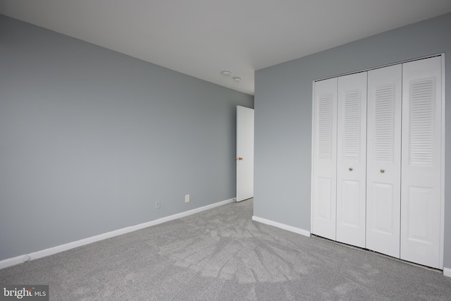 unfurnished bedroom featuring a closet and light carpet