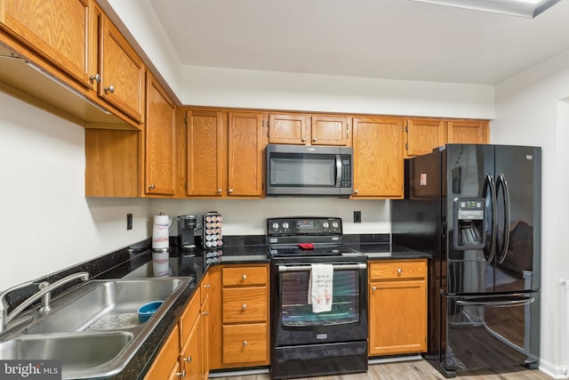 kitchen featuring brown cabinetry, light wood-style floors, a sink, and black appliances